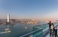 a couple standing on the edge of a balcony overlooking a river at Four Seasons Hotel Hong Kong in Hong Kong