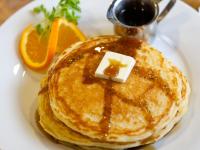 a plate with a stack of pancakes with syrup and orange slices at Wyoming Inn of Jackson Hole in Jackson