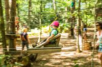 a young child riding on a zip line in the forest at Les Ecolodges de l&#39;Orbière in Forcé