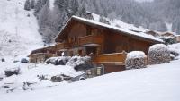 a snow covered log cabin with a snow covered roof at Le Lièvre Blanc, appartement N°2 in Les Contamines-Montjoie