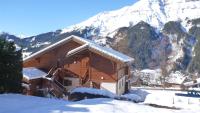 a log cabin in the snow with mountains in the background at Le Lièvre Blanc, appartement N°2 in Les Contamines-Montjoie
