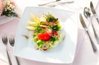 un plato blanco con una ensalada en una mesa en Hotel Wodnik, en Łeba