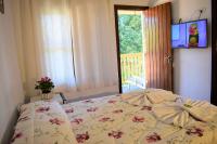 a bedroom with a bed with a tv on the wall at Pousada Sino dos Ventos in Campos do Jordão