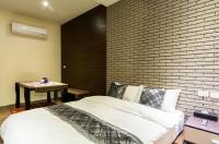 a bedroom with a white bed and a brick wall at Ritual and Breakfast in Hualien City