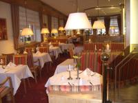 Un restaurante con mesas y sillas blancas y luces. en Ringhotel Weißer Hirsch, en Wernigerode