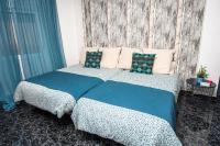 a bedroom with a bed with blue sheets and pillows at Hostal Caminito del Rey in Alora