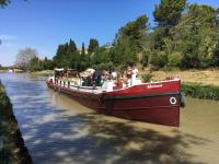 a red boat on a river with people on it at Bateau Mariance in Ginestas