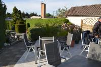 a man standing on a patio with chairs and tables at Pension zum Yachthafen in Waren