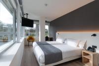 Un dormitorio con una cama grande y una ventana grande. en Hotel Distrito Oeste, en San Sebastián
