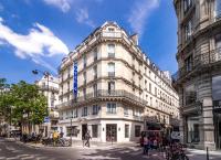 a tall white building with a blue sign on it at Hotel Marais Grands Boulevards in Paris