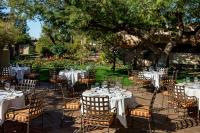 Un grupo de mesas y sillas en un jardín. en The Hermosa Inn, en Phoenix