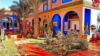 a house with blue and orange walls and palm trees at Riad Jasmine Sud in Zagora