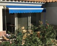 a patio with a blue awning and some plants at Résidence hôtelière A TRAMA in Bonifacio