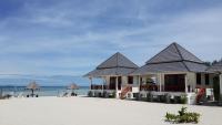 a building on the beach with the ocean in the background at Nice Sea Resort in Srithanu