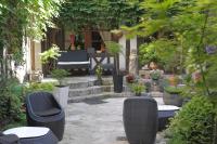 a patio with chairs and a bench and potted plants at Hôtel De La Cathédrale in Rouen