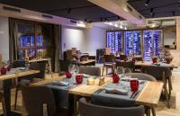 Un restaurante con mesas y sillas de madera y ventanas. en Hôtel Alparena & Spa - 4 étoiles, en La Rosière