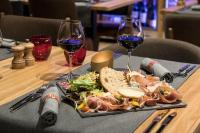 un plato de comida y dos copas de vino en una mesa en Hôtel Alparena & Spa - 4 étoiles, en La Rosière