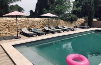 a swimming pool with chairs and umbrellas and a pink frisbee at Mas Guiraud, un instant rêvé in Beaucaire