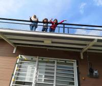 three girls standing on the balcony of a house at Jeram Tiny House in Jeram