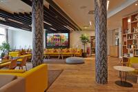 a lobby with yellow couches and a large screen at Novotel München City Arnulfpark in Munich