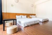 a bedroom with two beds and a table and a chair at 日安艸木環境友善民宿 Greener Homestay in Taitung City