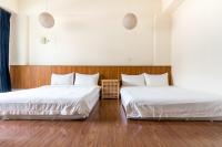 two beds in a room with white sheets and wood floors at 日安艸木環境友善民宿 Greener Homestay in Taitung City