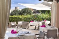 um restaurante com mesas brancas e cadeiras com flores cor-de-rosa em Hotel Corallaro em Santa Teresa Gallura