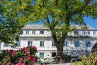 un árbol frente a un edificio blanco con flores rosas en Verkshotellet Jørpeland, en Jørpeland