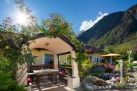 Un jardín con un arco y una mesa y flores. en Relais de la Sarvaz, en Saillon