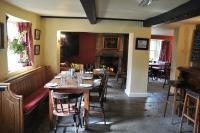 a dining room with tables and chairs and a fireplace at The Red Lion Inn in Babcary