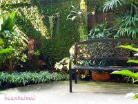 a bench in a garden with plants and a statue at Baan Baimai Boutique Room in Phra Nakhon Si Ayutthaya