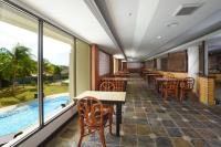a restaurant with tables and chairs and a swimming pool at De Greenish Village Langkawi in Kuah