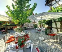 a patio with tables and chairs and an umbrella at Landhotel Hauer in Pleisweiler-Oberhofen