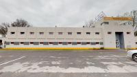 a white building with a parking lot in front of it at Première Classe Reims Ouest - Tinqueux in Reims