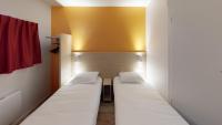 a pair of beds in a room with a yellow wall at Première Classe Reims Ouest - Tinqueux in Reims
