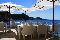 a restaurant with white tables and chairs and umbrellas at Hotel Bellevue Dubrovnik in Dubrovnik