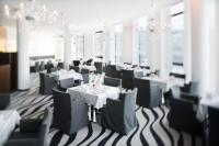 uma sala de jantar com mesas e cadeiras brancas em Mövenpick Hotel Stuttgart Airport em Estugarda