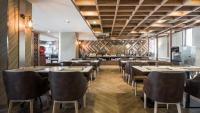a restaurant with wooden floors and tables and chairs at Zayn Hotel Bangkok - Airport Link Access in Bangkok