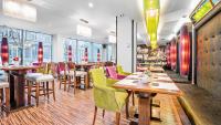 ein Restaurant mit Holztischen und bunten Stühlen in der Unterkunft Don Prestige Residence in Posen