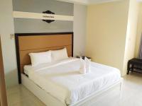 Un dormitorio con una cama blanca con dos zapatos blancos. en Boonbundal Hotel, en Roi Et