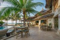an outdoor patio with tables and chairs and the ocean at Sailing Club Resort Mui Ne in Mui Ne