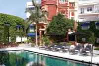 Una piscina con sillas y sombrillas frente a un edificio. en Hotel Medium Sitges Park, en Sitges