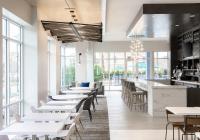 ein Restaurant mit weißen Tischen und Stühlen und Fenstern in der Unterkunft Hyatt Place Sandestin at Grand Blvd in Destin