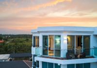 a house with a balcony with a sunset in the background at CASAMIA Oceanfront Condos Nilaveli in Nilaveli