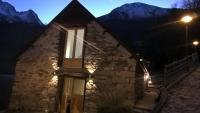 a stone building with a window at night with mountains at superbe grange rénovée in Grust