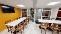 a dining room with tables and chairs and a flat screen tv at Premiere Classe Cambrai Proville in Cambrai