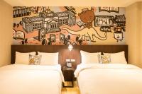 two beds in a hotel room with a mural on the wall at Just Live Inn-Taipei Station in Taipei