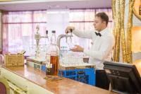 Un hombre con camisa blanca y corbata está vertiendo agua en vasos. en Hotel Kyiv, en Kiev