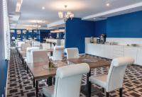 Hotel Sękowski في ليجنيكا: غرفة طعام مع كراسي وطاولات بيضاء وجدار أزرق