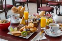 a table with breakfast foods and cups of orange juice at The Originals City, Hôtel Hélios, Roanne Nord (Inter-Hotel) in Mably